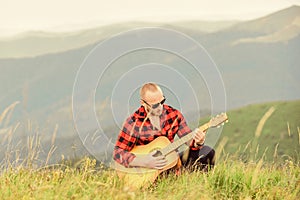 In unison with nature. Musician hiker find inspiration in mountains. Keep calm and play guitar. Man with guitar on top