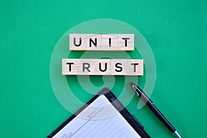 `Unit Trust` word on wood block with green background flat lay concept