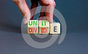 Unite or divide symbol. Concept word Unite or Divide on wooden cubes. Beautiful grey table grey background. Businessman hand.