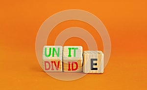 Unite or divide symbol. Concept word Unite or Divide on wooden cubes. Beautiful orange table orange background. Business unite or