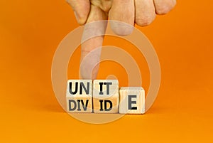 Unite or divide symbol. Concept word Unite or Divide on wooden cubes. Beautiful orange table orange background. Businessman hand.