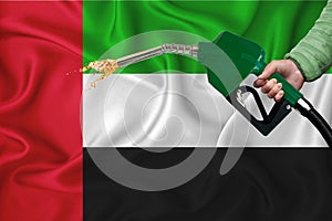 UNITED ARAB EMIRATES flag Close-up shot on waving background texture with Fuel pump nozzle in hand. The concept of design