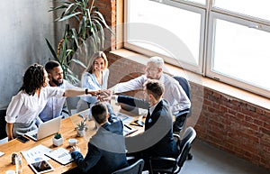 United Business Team Holding Hands Sitting Together In Modern Office