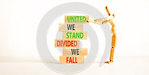 United or divided symbol. Concept words United we stand divided we fall on wooden blocks. Beautiful white table white background.