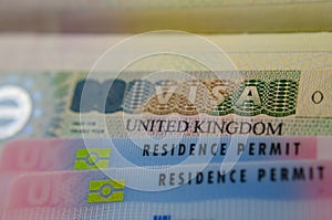 United Kingdom BRP Biometrical Residence Permit cards for Tier 2 work visa placed on top of UK VISA sticker in the passport. Clo