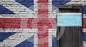 United Kingdom flag painted on brick wall and closed door with medical mask protected