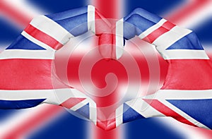 United kingdom flag painted on hands forming a heart on blurred Union Jack background, UK patriotism concept