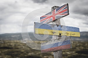 united kingdom, ukraine russia flag on wooden signpost outdoors in nature.