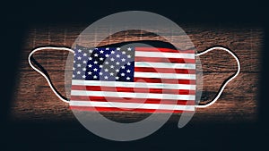 United States of America National Flag at medical, surgical, protection mask on black wooden background. Coronavirus Covidâ€“19,