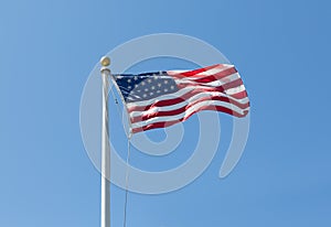 The United States flag on blue sky background, turned to the right