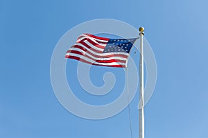 The United States flag on blue sky background, turned to the right