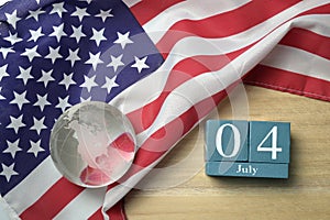 United states flag with crystal glass globe and wooden calendar on wood background