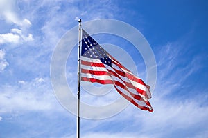 United States flag on a pole waving on blue sky background