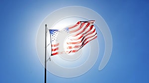 United States Flag waving in the wind with sun behind