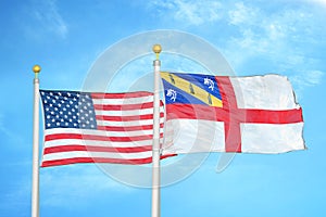 United States and Herm two flags on flagpoles and blue cloudy sky