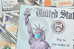 United States IRS Stimulus Check with Statue of Liberty Wearing Medical Face Mask Resting on Money photo