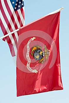 United States Marine Corps flag waving on blue sky background, close up, with American flag in background