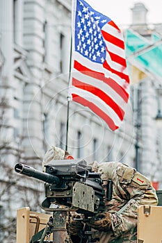 United States Marine Corps soldier on the top of a military vehicle mounting a machine gun with American flagAmerican flag