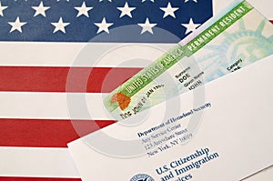 United States Permanent resident green card from dv-lottery lies on United States flag with envelope from Department of Homeland