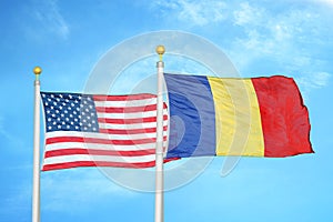 United States and Romania two flags on flagpoles and blue cloudy sky