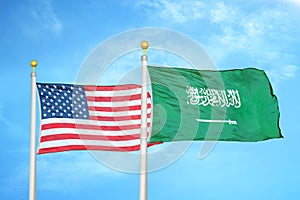 United States and Saudi Arabia two flags on flagpoles and blue cloudy sky