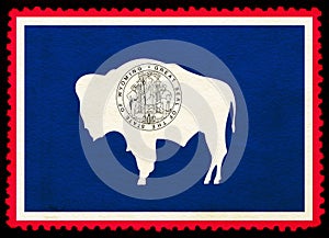 United States Wyoming state flag on the old grunge postage stamp isolated on black background