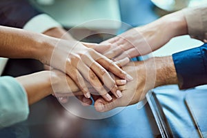 United for the teams success. Closeup shot of a group of executives standing with their hands together in a huddle.