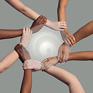 United together for a common cause. a group of hands holding on to each other at the wrist against a grey background.