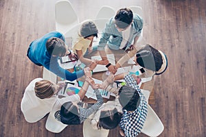 Unity and connection of people. Topview of partners putting their hands together, they sit at nice workstation, wearing casual cl