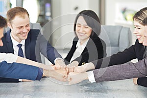 Unity and teamwork concept of young business people folding their hands together