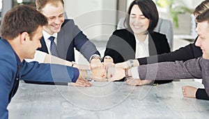 Unity and teamwork concept of young business people folding their hands together