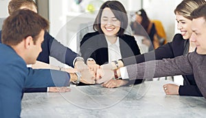 Unity and teamwork concept of young business people folding their hands together