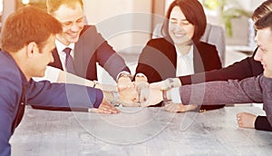 Unity and teamwork concept of young business people folding their hands together