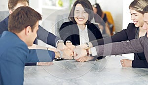 Unity and teamwork concept of young business people folding their hands together