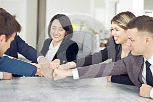 Unity and teamwork concept of young business people folding their hands together