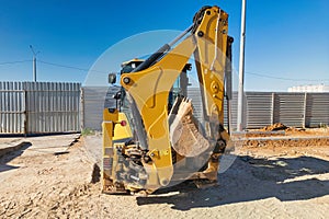 Universal excavator or loader with folded bucket at construction site. Universal construction equipment. Rental of construction