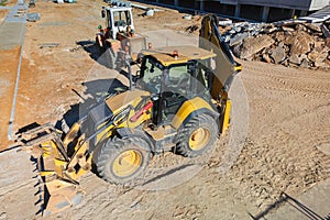 Universal excavator or loader with folded bucket at construction site. Universal construction equipment. Rental of construction