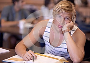 University, bored and portrait of man in classroom with books for studying, learning and research. Education, college