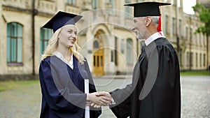 University chancellor giving diploma to student, congratulating and shaking hand photo