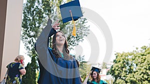 University graduates  throwing graduation hats in the air. Group of happy graduates in academic dresses near university building