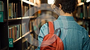 University Library: Student Walks Between Rows of Bookshelves Searching for Right Book Title for C