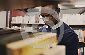 University, student and black man in a library reading and learning on campus for knowledge and education in college