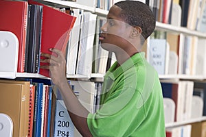 University student slecting book from library shel