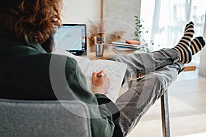 University student studying and making notes at campus using laptop