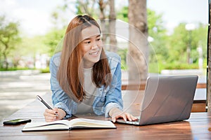 University student using internet search data for doing homework from computer in campus