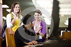 University students conversing by library computer photo