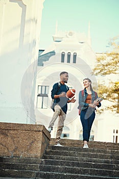 University, students and friends with a woman and man walking down stairs on campus for education. Learning, books and