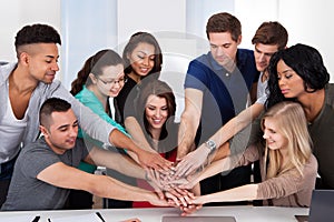 University students stacking hands at desk