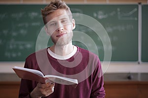 University young male professor teaching students in university holding notebook with chalk
