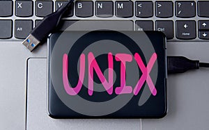 UNIX - acronym on an external drive in gray letters on the background of a laptop